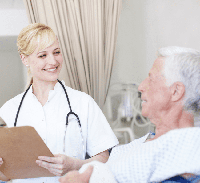 Nurse smiling at elderly patient in hospital.
