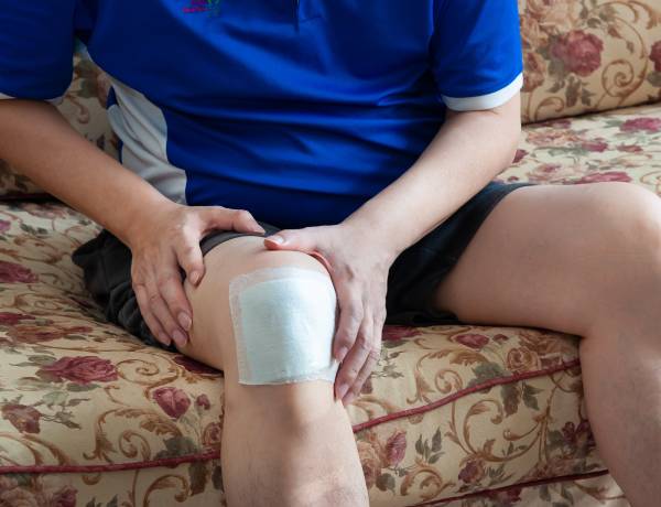 Person with bandaged knee sitting on couch.